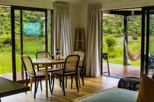 a dining room with a table and chairs and a porch at The Barn Cabins & Camp in Marahau