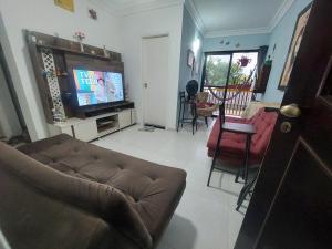 a living room with a couch and a flat screen tv at Apto Centro Bertioga (800 metros da praia) in Bertioga