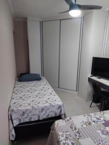 a bedroom with two beds and a desk with a computer at Apto Centro Bertioga (800 metros da praia) in Bertioga