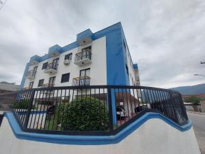 a large white building with a black fence in front of it at Apto Centro Bertioga (800 metros da praia) in Bertioga