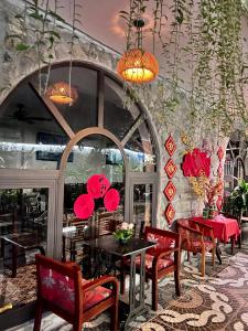 Tam Coc Paradise Homestay في نينه بينه: غرفة طعام مع كراسي حمراء وطاولات وجدار