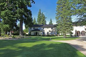 uma grande casa branca com árvores em frente em Hanmer Springs Hotel em Hanmer Springs