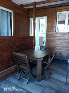 uma mesa de madeira e cadeiras no alpendre de um chalé em Le Domharry em Anse-Bertrand