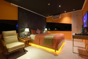 een slaapkamer met een bed en een stoel en een tv bij Chiic House 1 - Khách sạn tình yêu in Da Nang