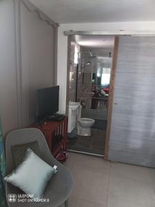 a bathroom with a toilet and a door with a television at Le Domharry in Anse-Bertrand