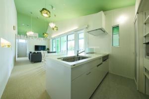 a white kitchen with a sink and a living room at Holiday House Green Garden in Gujo