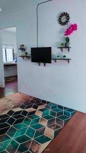 パンタイチェナンにあるLaman Hanaz - Homestay Auniの白い壁のリビングルーム(ラグ付)