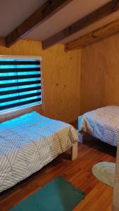 1 dormitorio con 2 camas y ventana en Cabaña Los Nietos, en Futaleufú