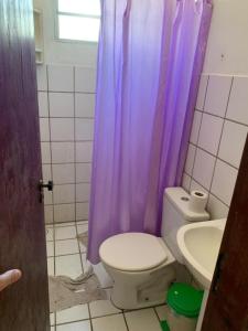 a bathroom with a toilet and a purple shower curtain at Itamaracá in Itamaracá