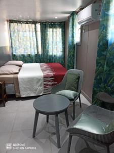 a bedroom with a bed and a table and chairs at Le Domharry in Anse-Bertrand