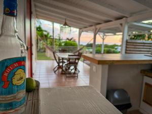 - une bouteille d'alcool assise sur une table à côté d'une terrasse couverte dans l'établissement Gîte Côté Mer - Vue mer, à Grand-Bourg