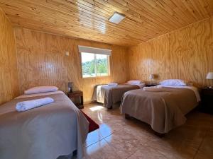 a room with three beds in a wooden room at Paraiso Patagonico in Chaitén