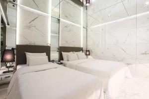 two beds in a room with white marble walls at Hotel Star Premier Yeoksam in Seoul