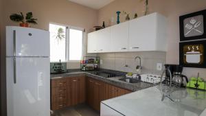 a kitchen with white cabinets and a white refrigerator at Paraíso de Maracajaú 4 in Maxaranguape