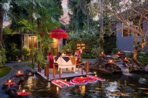 un jardín con mesa y sillas en un estanque en Tonys Villas & Resort Seminyak - Bali, en Seminyak