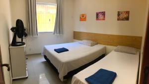 a room with two beds and a fan in it at Casa Amarela de Praia in Maricá +18 photos