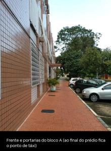 un trottoir en briques à côté d'un bâtiment avec des voitures garées dans l'établissement Boa Opção Asa Sul, à Brasilia