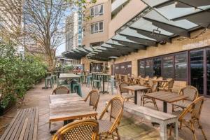 an outdoor patio with wooden tables and chairs at Comfy Studio Next to Chatswood Station in Sydney