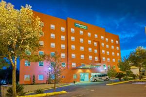 Un bâtiment orange avec une camionnette garée devant. dans l'établissement City Express Junior by Marriott Puebla FINSA, à Puebla