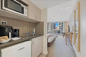 a kitchen with a sink and a living room at Comfy Studio Next to Chatswood Station in Sydney