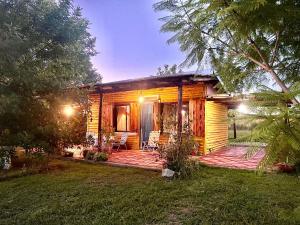 a small cabin with a deck and chairs in the yard at CABAÑA LA BOHEMIA in Colonia Hughes