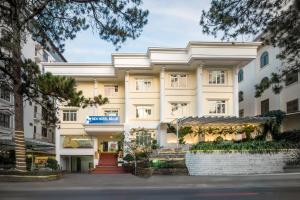 un grand bâtiment blanc avec des arbres devant lui dans l'établissement BIDV Central Da Lat Hotel, à Đà Lạt