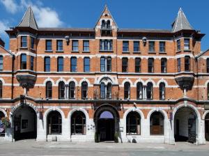 ein großes rotes Backsteingebäude mit einem Uhrturm in der Unterkunft Hotel Isaacs Cork City in Cork