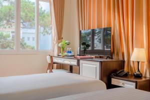 BIDV Central Da Lat Hotel في دالات: غرفة نوم بسريرين ومكتب فيه تلفزيون