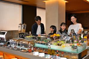 eine Gruppe von Menschen, die um ein Buffet mit Speisen stehen in der Unterkunft KAYA Kyoto Nijo Castle, BW Signature Collection by Best Western in Kyoto