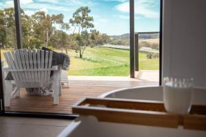 une chaise à bascule blanche assise sur une terrasse avec une grande fenêtre dans l'établissement kentonviewsestate, à Gumeracha