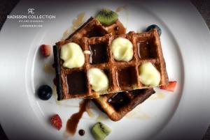a white plate with waffles with butter and berries at Radisson Collection Hyland Shanghai in Shanghai