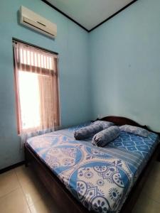 een slaapkamer met een bed met blauwe muren en een raam bij Guest House Djatis Purwo Wasito in Bojonegoro