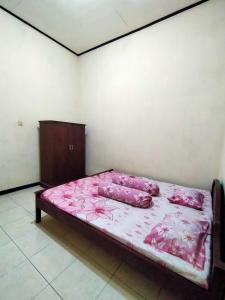 een bed in een kamer met roze lakens en kussens bij Guest House Djatis Purwo Wasito in Bojonegoro