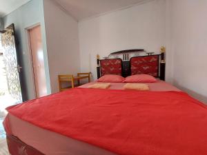 Un dormitorio con una gran cama roja con sábanas rojas en Maharani Homestay, en Gorontalo