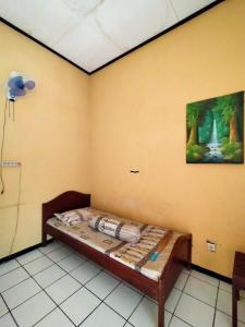 Guest House Djatis Purwo Wasito في Bojonegoro: سرير في غرفة مع لوحة على الحائط