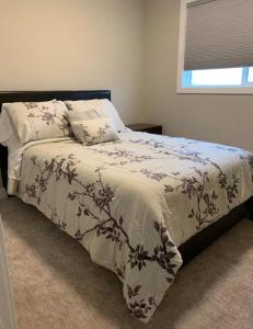 um quarto com uma cama com um cobertor e almofadas em New Townhouse in Red Deer em Red Deer