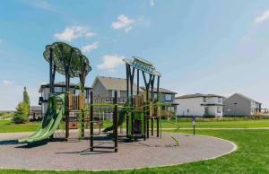 a playground with a slide in a park at New Townhouse in Red Deer in Red Deer