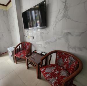 two chairs and a table and a television on a wall at TUAN Central Hotel in Hanoi