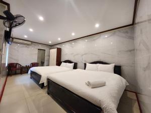 a bedroom with two beds and a stone wall at TUAN Central Hotel in Hanoi