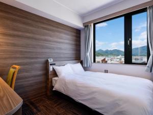 um quarto com uma cama e uma grande janela em ホテル紀伊田辺 em Tanabe