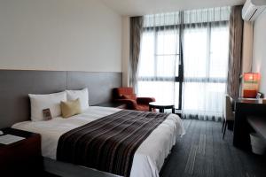 台東市にあるIta taiwan indigenous cultural resortの大きなベッドと椅子が備わるホテルルームです。