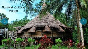 uma pequena cabana com um telhado de palha ao lado de uma palmeira em Imperial Suites Apartments em Kuching