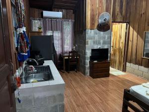 uma cozinha com um lavatório e uma televisão num quarto em Cabañas Hospedaje la Reserva em Hojancha
