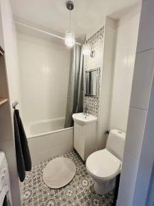 a white bathroom with a toilet and a bath tub at Apartament z panoramicznym widokiem w Centrum in Warsaw