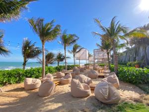 a row of white chairs on a beach with palm trees at APEC MANDALA CONDOTEL - Mui Ne in Mui Ne