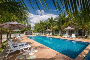 a pool with chairs and umbrellas and palm trees at Mook Anda Villa in Ao Nang Beach