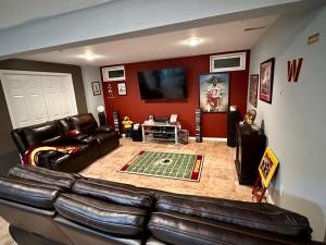 a living room with a leather couch and a flat screen tv at The Oasis@Woodyard in Upper Marlboro