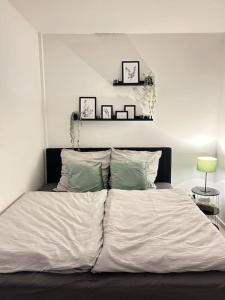 een slaapkamer met een bed met witte lakens en groene kussens bij Superior - Central Rooftop - 20min to Hamburg in Elmshorn
