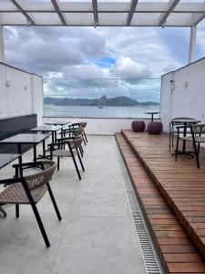 a patio with tables and chairs and a view of the water at Apartamento Praia Flamengo Charme in Rio de Janeiro