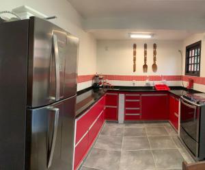 uma cozinha com armários vermelhos e um frigorífico de aço inoxidável em Casa Pé na Areia Sapê em Ubatuba